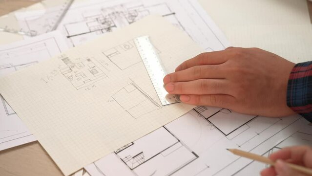 Professional engineer team discussion about house design on meeting table with architectural equipment and building blueprint scatter around at modern office. Focus on hand. Closeup. Delineation.