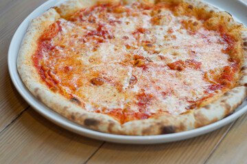 Pizza margherita in a plate on a wooden table