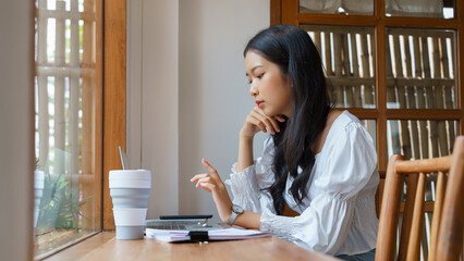 Young asian businesswoman reading market data of business to thinking about investment and planning...