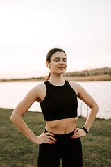 Fototapeta na wymiar A young woman in sportswear does fitness exercises at sunset in nature. Healthy lifestyle concept. Fitness and sport