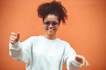 African ethnicity young woman in stylish sunglasses, with curly hair tied up in high ponytail,...