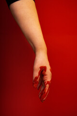 The bloodied hand of a caucasian girl. Red blood trickles from the female fingers. Halloween horror concept. - obrazy, fototapety, plakaty