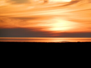Fototapeta premium Scenic view of a magical orange sunrise over the silhouette of the field