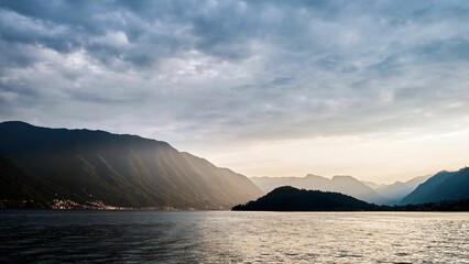 Beautiful shot of Lake Como surrounded by mountains against a cloudy sky during the sunset