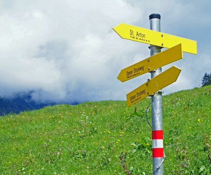 Daytime view of a signpost in St. Anton, Austria in a grass field on a sunny day