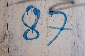 Blue number 87 paint on a dirty wall