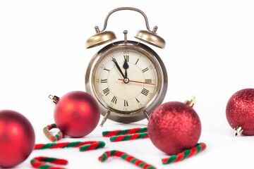 Alarm clock showing New Year arrival with red Christmas decoration on isolated white background