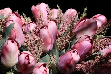 An illuminated bouquet of artificial tulips,on a black background, the concept of an elegant present