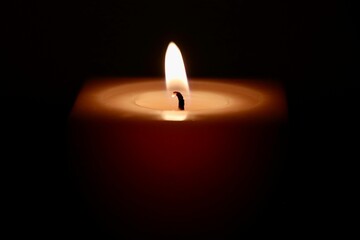 Macro shot of a candle's flame in the darkness, the concept of a hope in the most difficult times