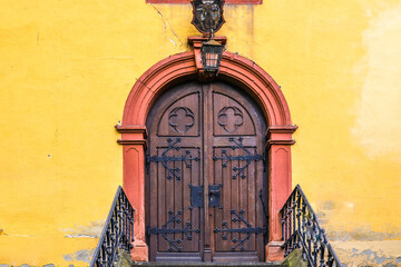 Historische Holztür in gelben Gebäude mit Lampe über dem Eingang