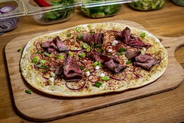 Closeup shot of a French pizza with Tarte Flambe with Roastbeef and purple curry