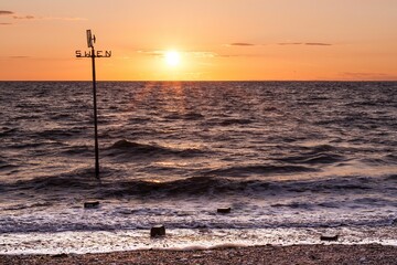 Golden sunset over Hunstanton Beach with a weathervane - obrazy, fototapety, plakaty