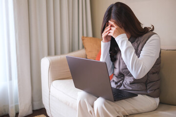 A woman get headache and stressed while working online on laptop computer at home