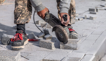 Worker cutting granite slab with angle grinder in construction site