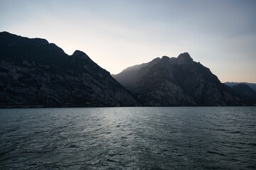 Landscape of lake Garda surrounded by hills under a blue sky and sunlight in Italy