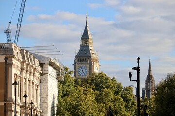 Scenic view of the Big Ben on blue sky background with green trees in front in London, England