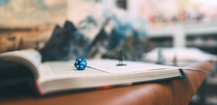 Blue dice D20 place on adventure story TTRPG book role playing tabletop game and board games