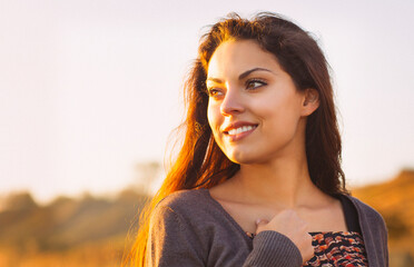 Portrait of the beautiful brunette woman at the windy autumn day relaxing on coast