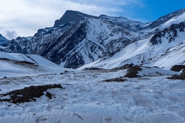 Fototapeta premium Image of mountains covered by snow under the cloudy blue sky.