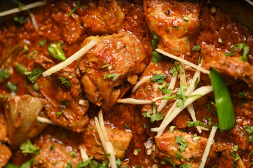 Spicy red boneless chicken handi topped with ginger closeup