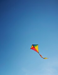 A colorful kite flies high against the clear blue sky, offering a playful and uplifting scene