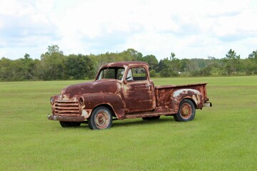 Old rusty pickup car in the green field.