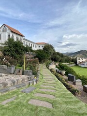 Vertical shot of a footpath on the green lawn with town buildings in the background. Cusco, Peru.