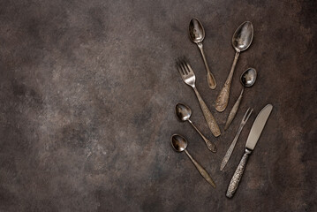 Vintage cutlery on a dark brown rustic background. Top view, flat lay, copy space.