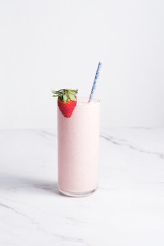 Strawberry milkshake with straw and fresh strawberry