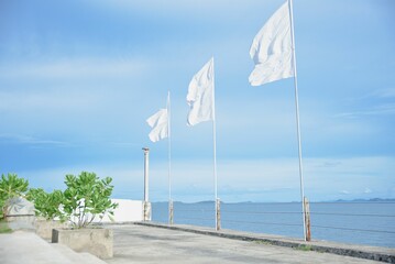 Scenic view of three white flags waving by the coast of a beach