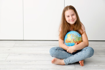 little cute girl sitting on the floor hugging a globe