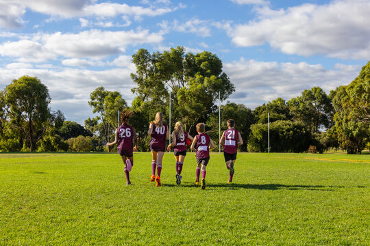 with numbers on the back of their jerseys five schoolchildren jog towards the goalposts