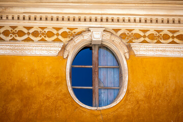 Detail of oval window on old yellow facade in a house in the old town of Caravaca, Region of...
