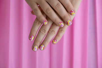 Pastel softness colorful manicured nails on pink background. Woman showing her new summer manicure in colors of pastel palette. Simplicity decor fresh spring vibes earth-colored neutral tones