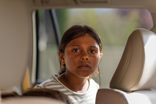 head and shoulders of aboriginal child with dirty face sitting in back seat of a car