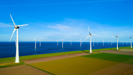 A stunning scene unfolds as a group of windmills stand tall in a field next to the ocean in the Netherlands Flevoland during the vibrant season of Spring. earth day, eco friendly, green energy