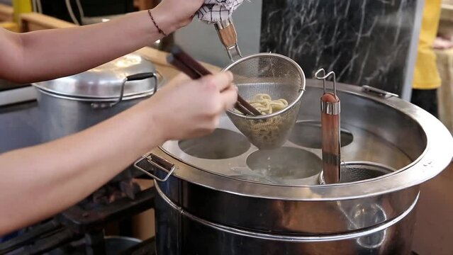 Cooking rubber noodles using a noodle strainer and putting them in a stainless steel bowl, street food