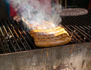 Sausages grilled on a smoky outdoor barbecue, with visible grill marks and attention to sizzling food in Mexico