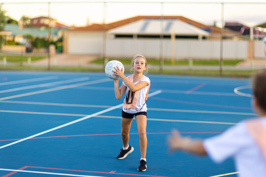 ten year old girl ready to throw netball to teammate at training