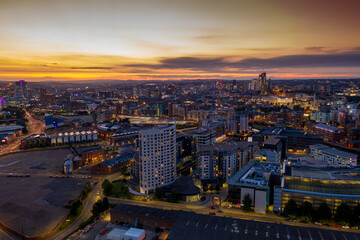 Aerial night time photo taken at sunset of the area in Leeds known as The Leeds Dock showing the whole of the West Yorkshire city with the sun setting in the background
