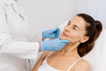 Close-up. Before the procedure for facial contouring or plastic surgery, the cosmetologist makes...
