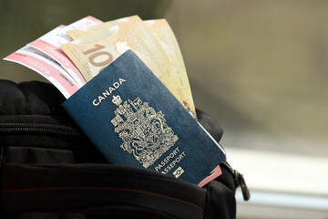Naklejka premium Canadian passport and dollar money bills with airline tickets on backpack close up