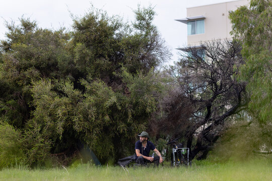 Homeless man with a beer sitting on a milk crate in the bush