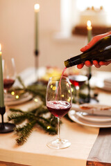 Candles and wine on Christmas table. Man serving wine during dinner