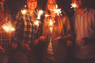 Young people with sparklers having fun on outdoor party