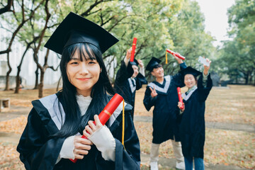 An Asian female university student gazes into the camera at the graduation ceremony, her eyes...