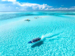 Aerial view of floating boat in transparent azure water on sunny summer day. Mnemba island,...
