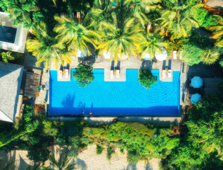 Aerial view of swimming pool, sunbeds and umbrellas, green palms, sandy beach in luxury resort at sunset in summer. Nungwi, Zanzibar island. Top drone view. Tropical landscape. Exotic. Sea coast - 784413154