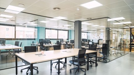Interior of spacious creative coworking workspace with desks and chairs in glass cabins