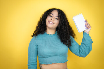 African american woman wearing casual sweater over yellow background smiling and showing blank...